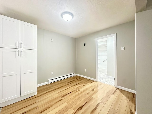 300 Smithfield Rd Unit B3-18, North Providence, RI 02904 - unfurnished bedroom with a baseboard radiator, light wood-style floors, baseboards, ensuite bath, and a textured ceiling
