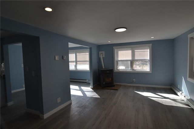115 Sherman Farm Rd, Burrillville, RI 02830 - unfurnished living room with a baseboard heating unit, a wood stove, wood finished floors, and baseboards