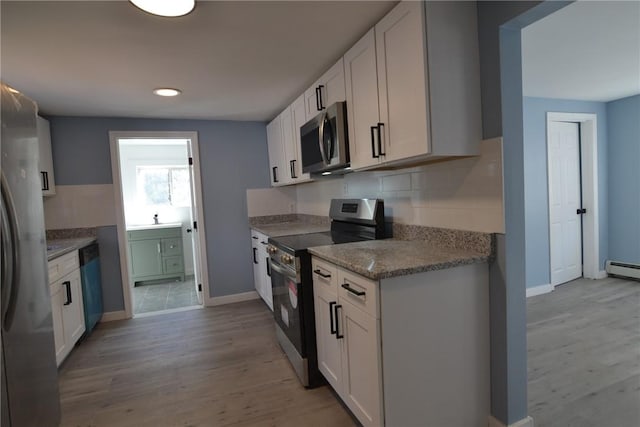 115 Sherman Farm Rd, Burrillville, RI 02830 - kitchen featuring stainless steel appliances, tasteful backsplash, light wood-style floors, white cabinets, and baseboards