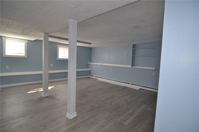 115 Sherman Farm Rd, Burrillville, RI 02830 - below grade area with baseboard heating, a textured ceiling, wood finished floors, healthy amount of natural light, and baseboards