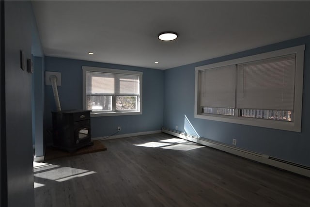 115 Sherman Farm Rd, Burrillville, RI 02830 - unfurnished living room with a baseboard radiator, wood finished floors, a wood stove, and baseboards