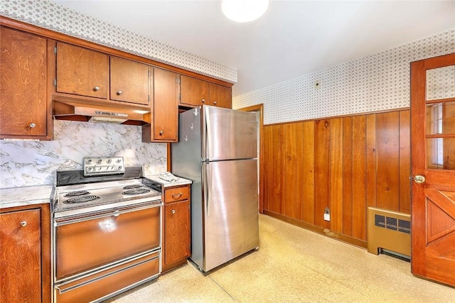 14 Manchester St, Bristol, RI 02809 - kitchen featuring range with electric stovetop, freestanding refrigerator, radiator, under cabinet range hood, and brown cabinetry