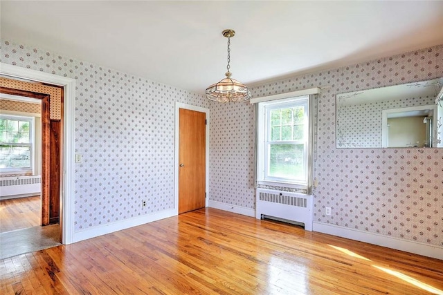 14 Manchester St, Bristol, RI 02809 - unfurnished dining area with radiator heating unit, wood finished floors, wallpapered walls, a chandelier, and baseboards