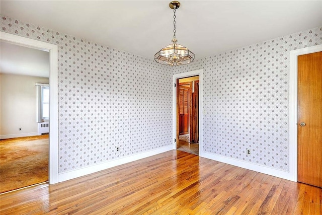14 Manchester St, Bristol, RI 02809 - spare room featuring wallpapered walls, a chandelier, light wood-style floors, baseboards, and radiator heating unit