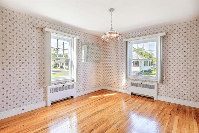 14 Manchester St, Bristol, RI 02809 - unfurnished dining area featuring radiator, wallpapered walls, a chandelier, and wood finished floors