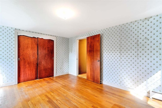 14 Manchester St, Bristol, RI 02809 - unfurnished bedroom featuring wallpapered walls, wood finished floors, baseboard heating, a closet, and baseboards