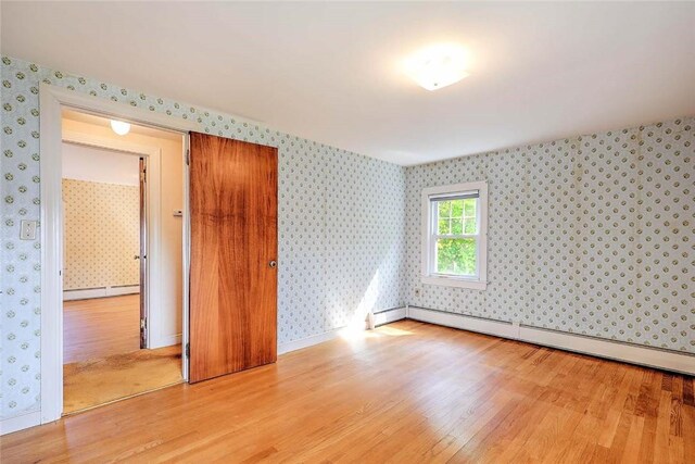 14 Manchester St, Bristol, RI 02809 - spare room with wood finished floors, wallpapered walls, a baseboard heating unit, and baseboards