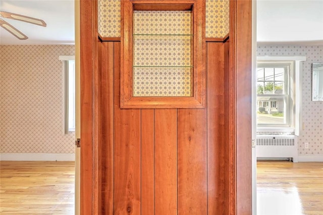 14 Manchester St, Bristol, RI 02809 - detailed view of radiator heating unit, wallpapered walls, wood finished floors, ceiling fan, and baseboards