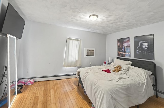 176 Warwick Ave, Cranston, RI 02905 - bedroom with baseboard heating, a wall mounted air conditioner, wood-type flooring, and a textured ceiling