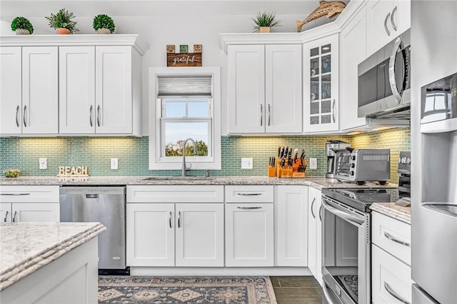 32 Breach Dr, Westerly, RI 02891 - kitchen featuring appliances with stainless steel finishes, a sink, white cabinetry, glass insert cabinets, and decorative backsplash