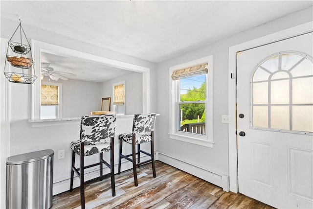foyer entrance featuring a baseboard heating unit, wood finished floors, and a ceiling fan