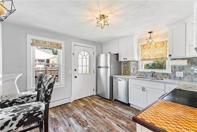 kitchen featuring stainless steel appliances, a sink, a baseboard radiator, dark wood-style floors, and decorative backsplash