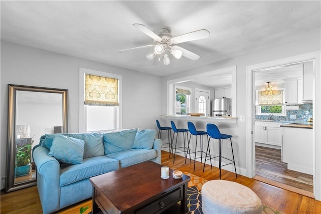 living area featuring plenty of natural light, wood finished floors, and a ceiling fan