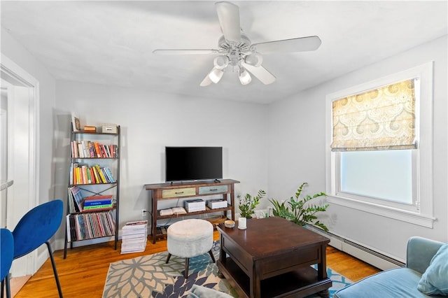 living area with wood finished floors, baseboard heating, and a ceiling fan