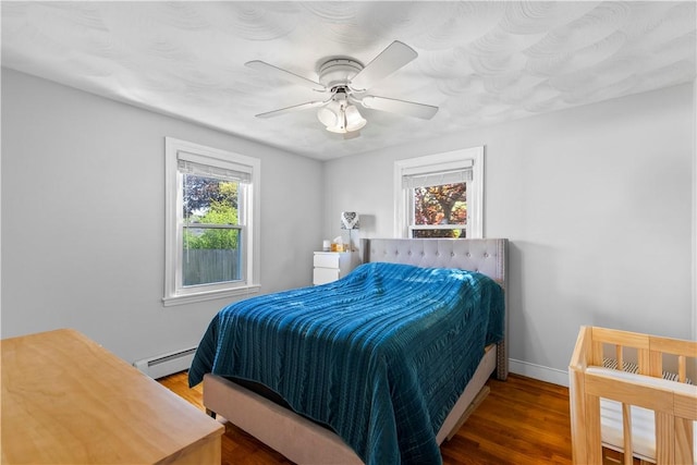 bedroom with wood finished floors, baseboard heating, baseboards, and a ceiling fan