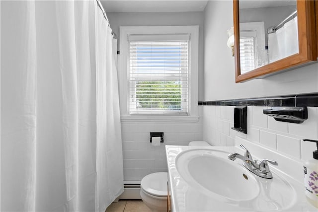 bathroom featuring a baseboard heating unit, toilet, tile walls, tile patterned flooring, and wainscoting