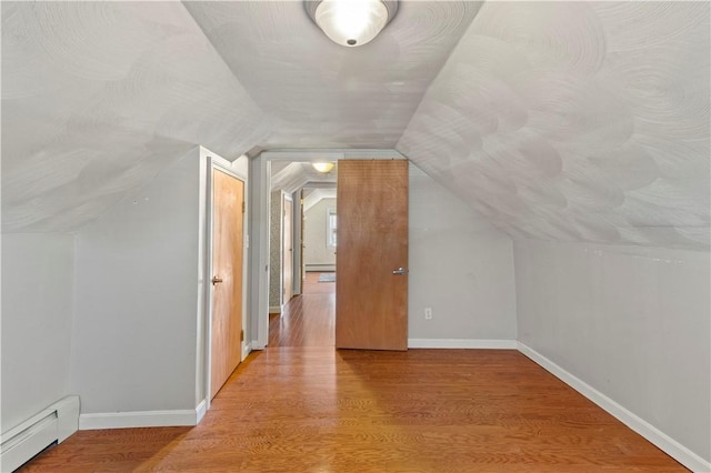 bonus room featuring baseboard heating, vaulted ceiling, wood finished floors, and baseboards