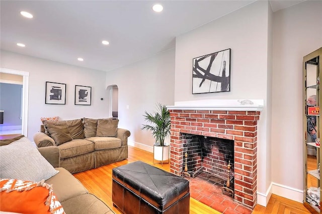 living room with arched walkways, a fireplace, baseboards, recessed lighting, and wood finished floors