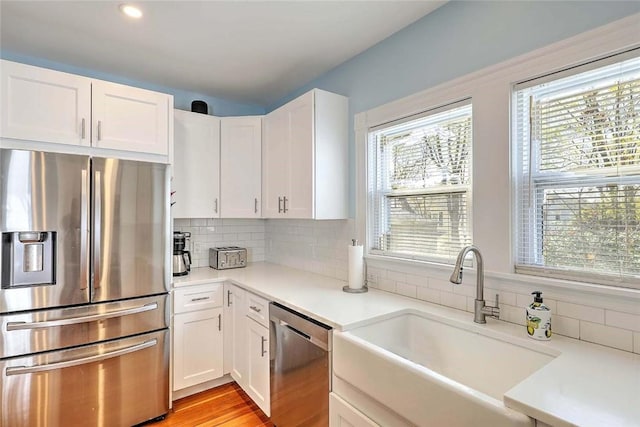 kitchen featuring stainless steel appliances, a sink, white cabinets, light countertops, and recessed lighting