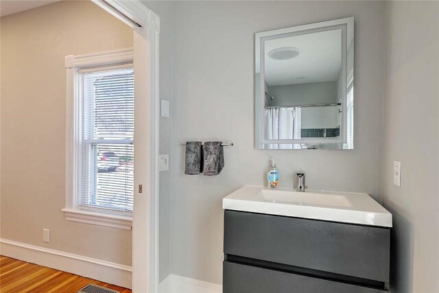 bathroom featuring healthy amount of natural light, baseboards, wood finished floors, and vanity