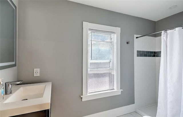 full bathroom featuring tiled shower and vanity