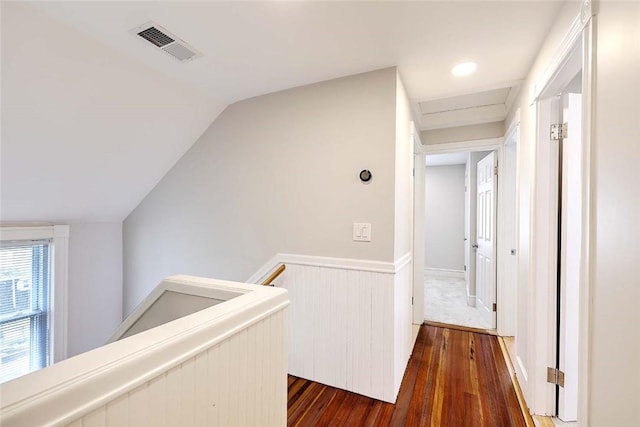 hall with an upstairs landing, dark wood finished floors, and vaulted ceiling