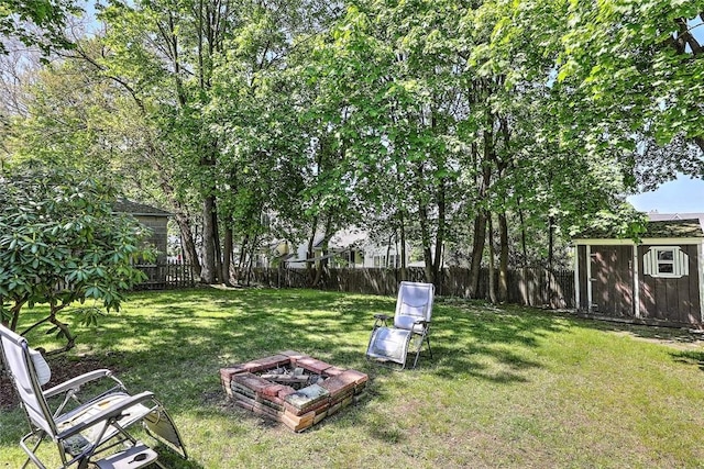 view of yard with a fire pit, a storage shed, and an outbuilding