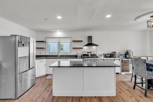 kitchen with appliances with stainless steel finishes, wall chimney range hood, open shelves, a sink, and a center island