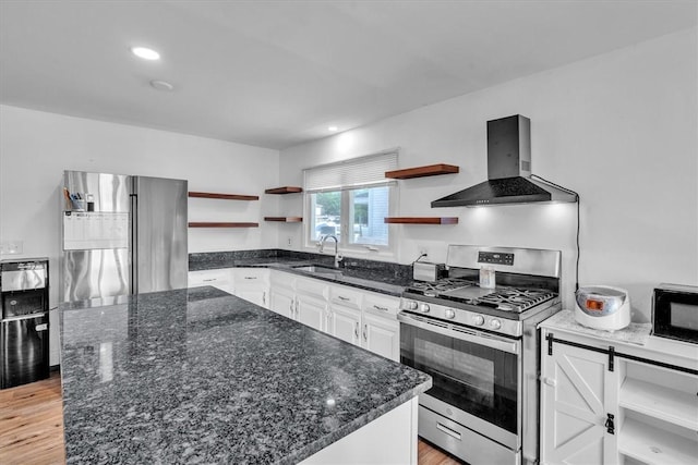 kitchen with open shelves, stainless steel gas stove, wall chimney range hood, a sink, and black microwave