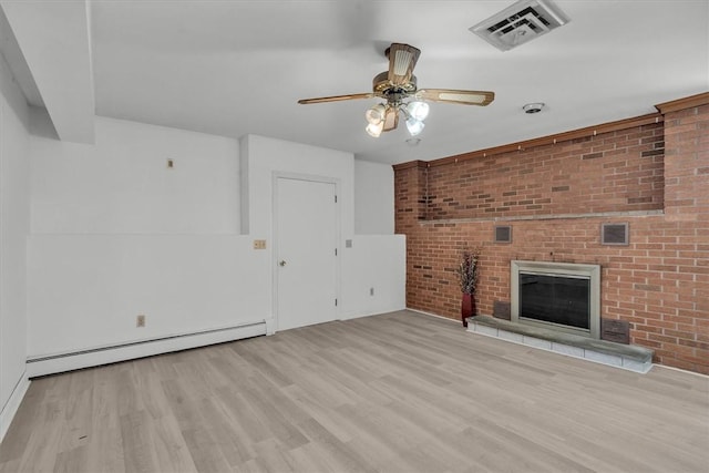 unfurnished living room featuring baseboard heating, wood finished floors, a ceiling fan, a brick fireplace, and brick wall