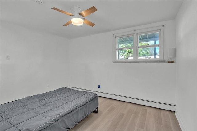 bedroom featuring a baseboard heating unit, light wood-type flooring, baseboards, and ceiling fan