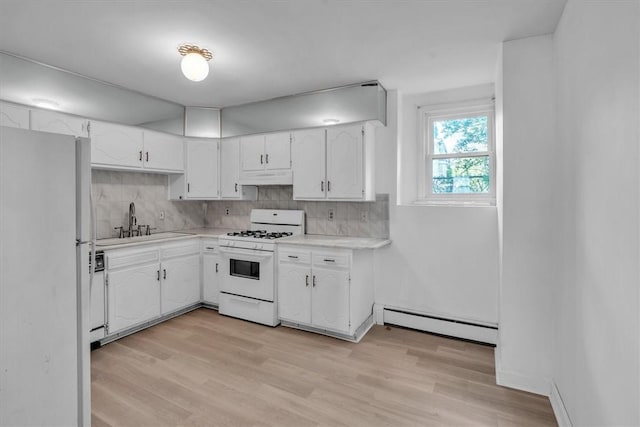 kitchen with white appliances, a sink, under cabinet range hood, baseboard heating, and backsplash