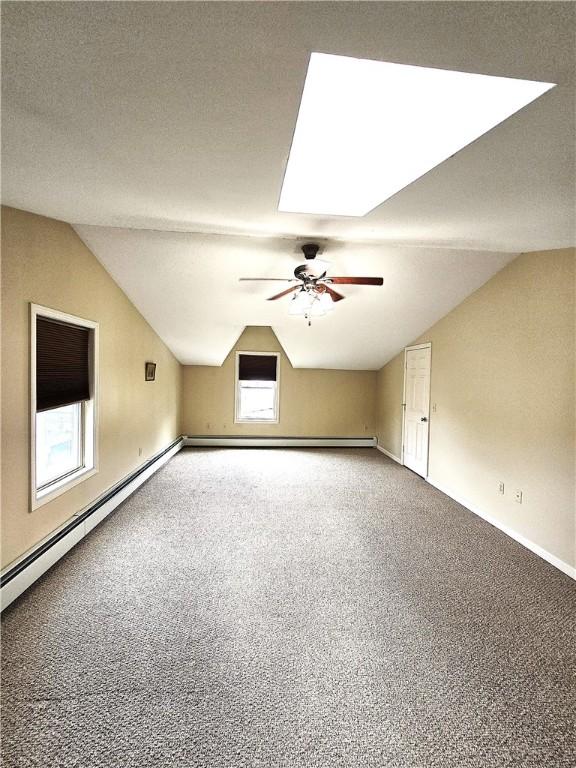 94 Barton St, Pawtucket, RI 02860 - bonus room with vaulted ceiling, carpet floors, ceiling fan, a skylight, and a baseboard heating unit