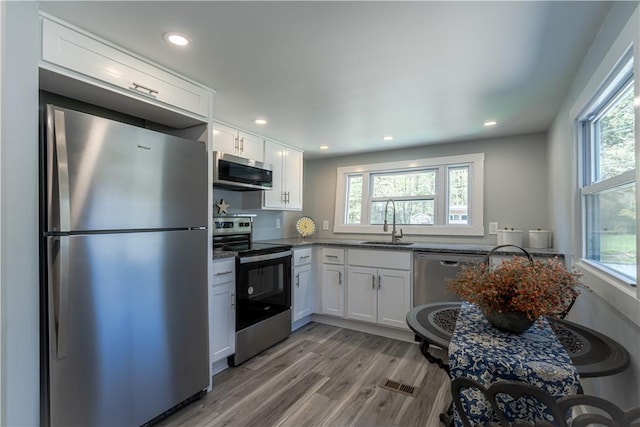 67 Linda Dr, Coventry, RI 02816 - kitchen with stainless steel appliances, a sink, white cabinets, light wood-style floors, and recessed lighting