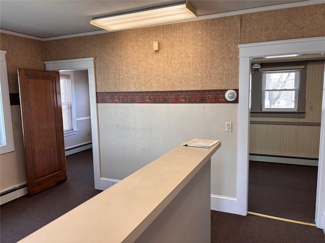 hall featuring a baseboard heating unit, dark colored carpet, wallpapered walls, crown molding, and baseboards
