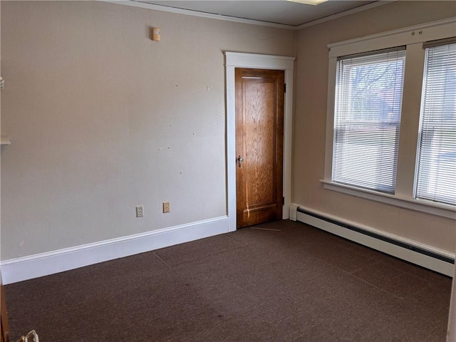 spare room featuring a baseboard radiator, dark colored carpet, crown molding, and baseboards
