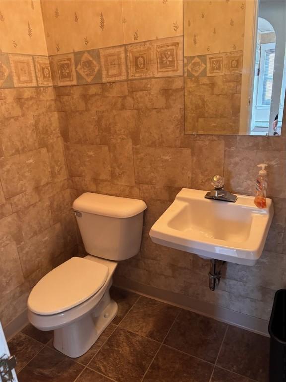 bathroom featuring tile walls, a sink, and toilet