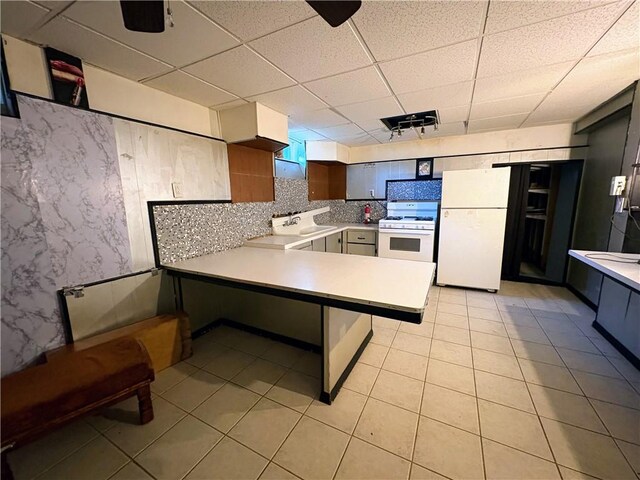 74 Lubec St, Providence, RI 02904 - kitchen with white appliances, a peninsula, light tile patterned floors, light countertops, and a paneled ceiling