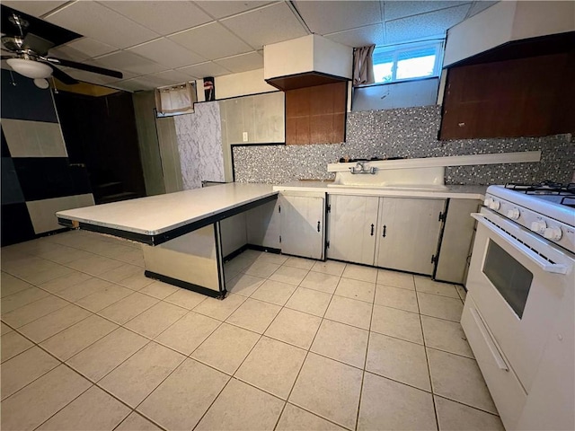 74 Lubec St, Providence, RI 02904 - kitchen with white gas range oven, a peninsula, light countertops, light tile patterned floors, and a drop ceiling