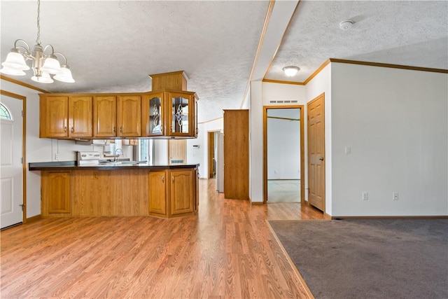 kitchen with brown cabinets, crown molding, a chandelier, glass insert cabinets, and light wood-type flooring