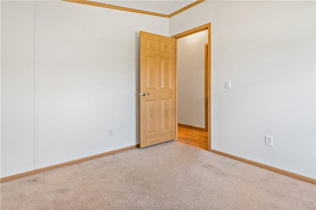 carpeted spare room with ornamental molding and baseboards
