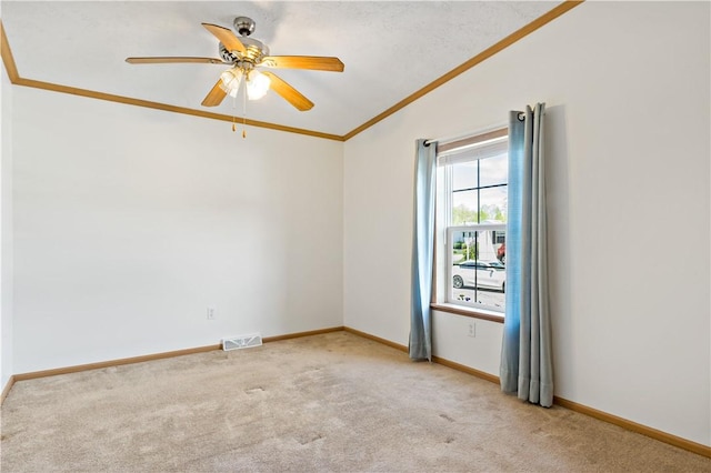 carpeted spare room with vaulted ceiling, crown molding, ceiling fan, and baseboards
