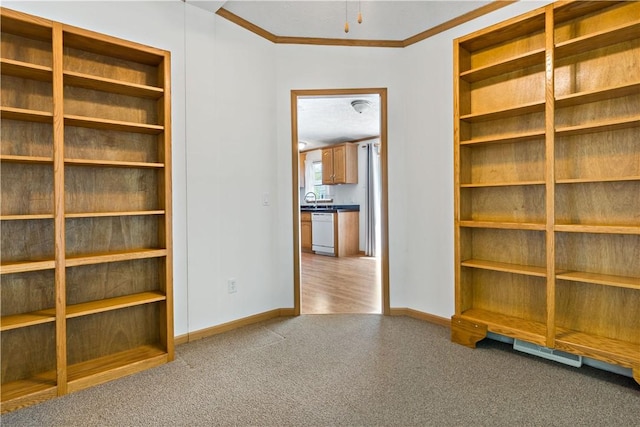 unfurnished bedroom with carpet, crown molding, baseboards, and a sink