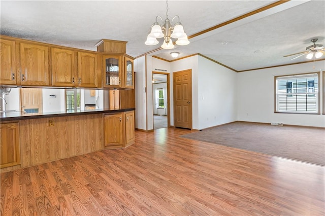 kitchen with brown cabinets, ornamental molding, a chandelier, healthy amount of natural light, and dark countertops