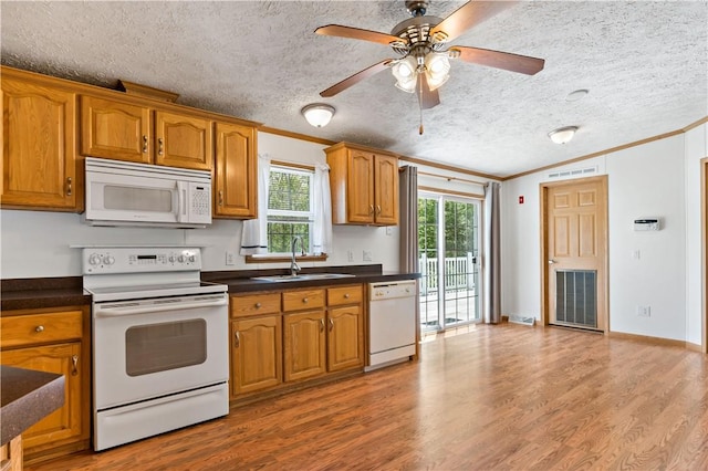 kitchen with white appliances, crown molding, a sink, brown cabinetry, and a textured ceiling