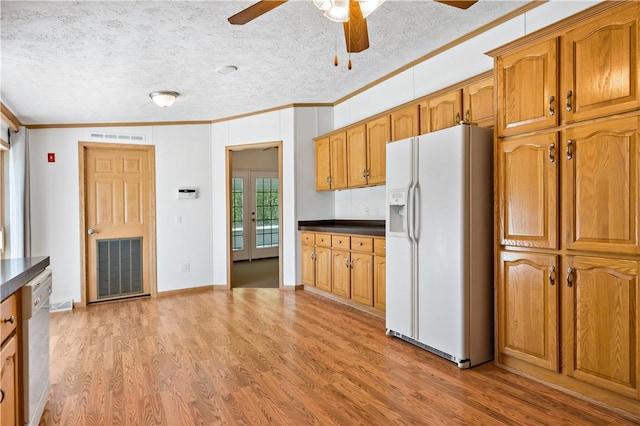 kitchen with white appliances, crown molding, a ceiling fan, dark countertops, and light wood finished floors