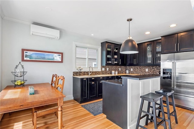 29 Webster St, Newport, RI 02840 - kitchen with high end fridge, an AC wall unit, light wood-style flooring, a breakfast bar, and backsplash