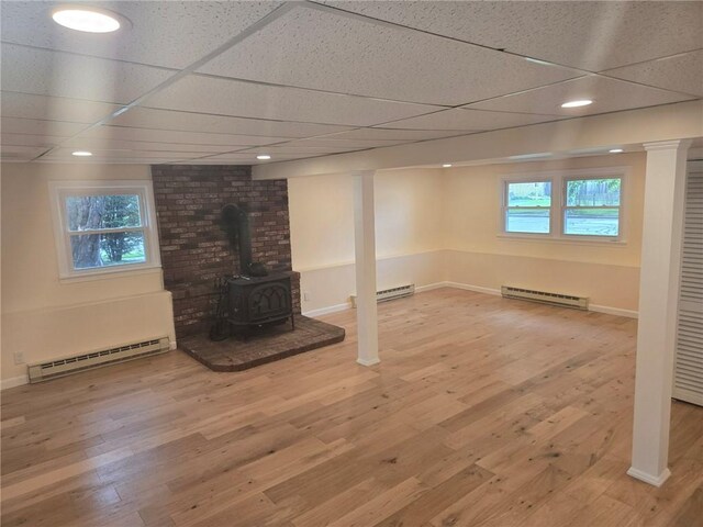 8 Centennial St, Coventry, RI 02816 - below grade area featuring a baseboard heating unit, baseboard heating, a wood stove, wood finished floors, and a paneled ceiling