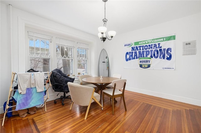 dining space featuring baseboards, a chandelier, and wood finished floors