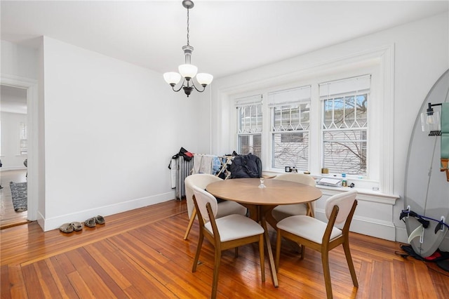 dining space with a chandelier, baseboards, and wood finished floors
